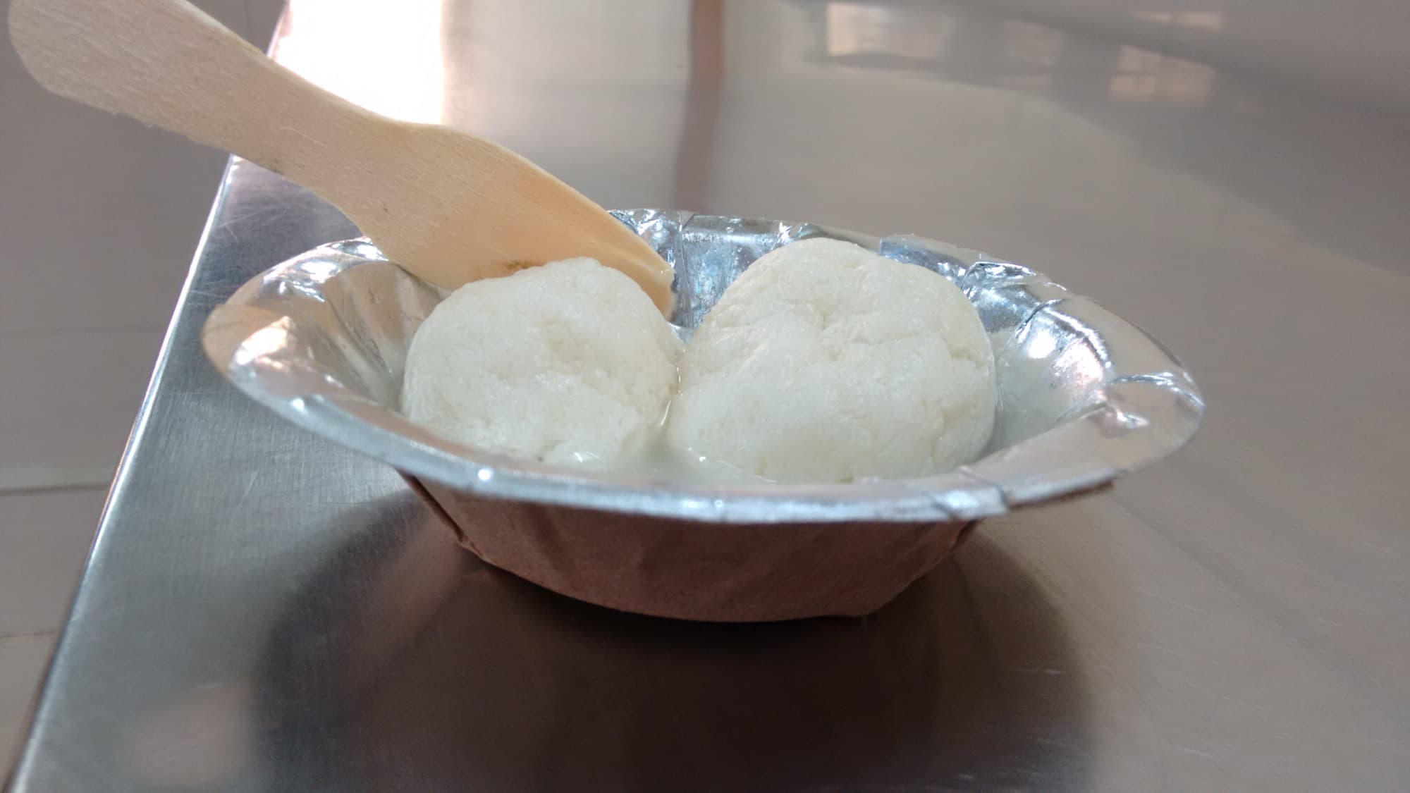 Two rasgullas in syrup in a foil bowl at Annapurna Sweets in Chandni Chowk, Delhi