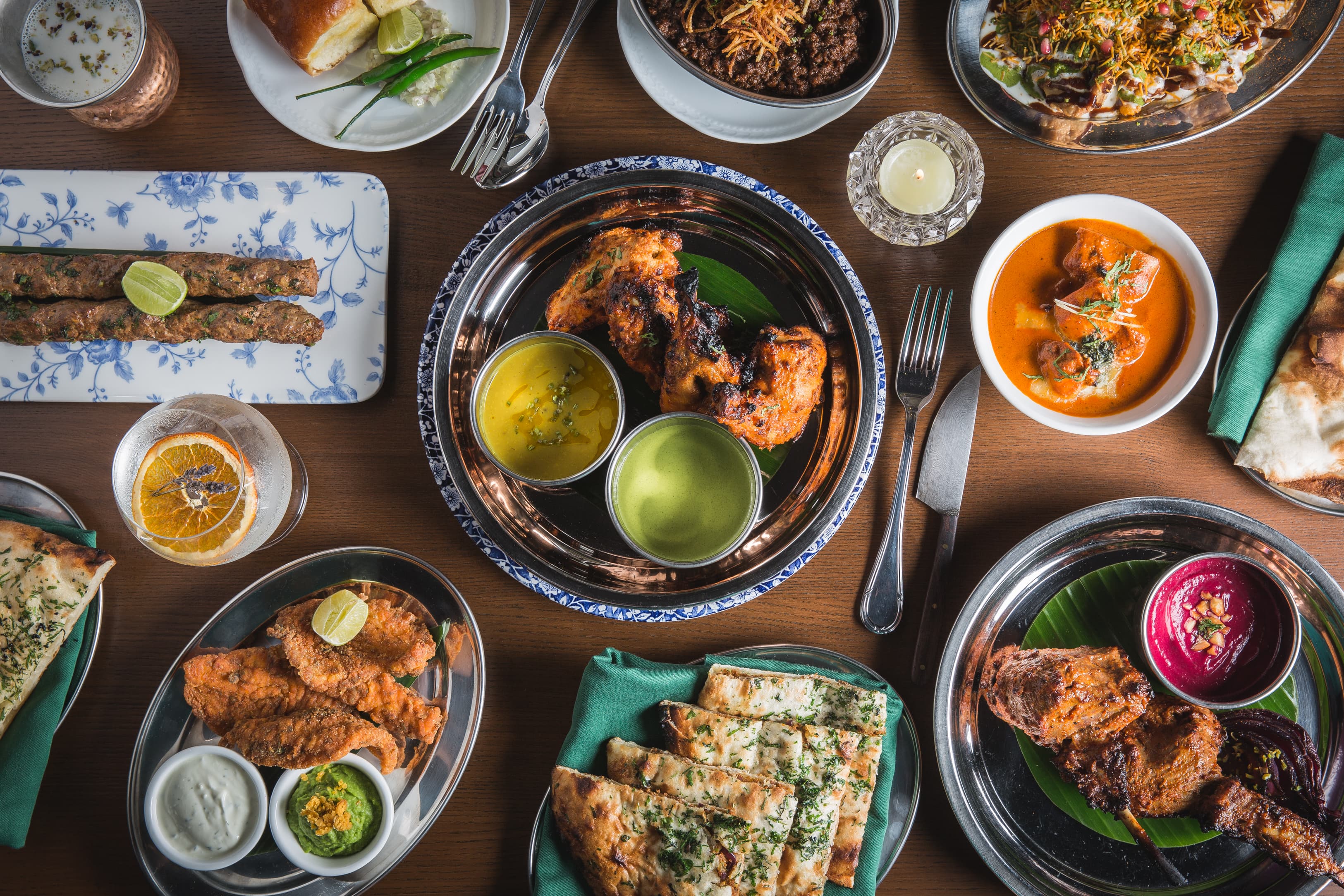 Punjabi restaurant spread with naan, dal, kebabs, curries, chutneys, and lassi